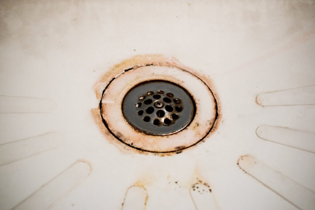 Drain de douche encrassé avec des signes de rouille et de calcaire, indiquant une canalisation probablement bouchée.